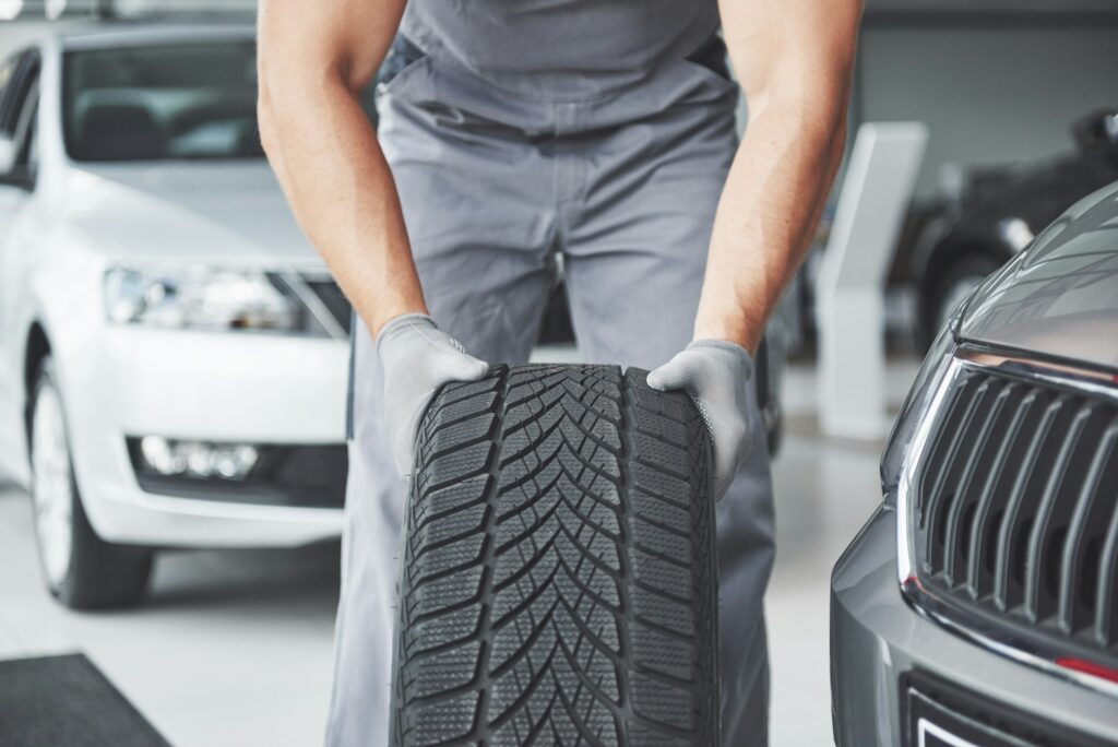 Mechanic holding a tire tire at the repair garage. replacement of winter and summer tires